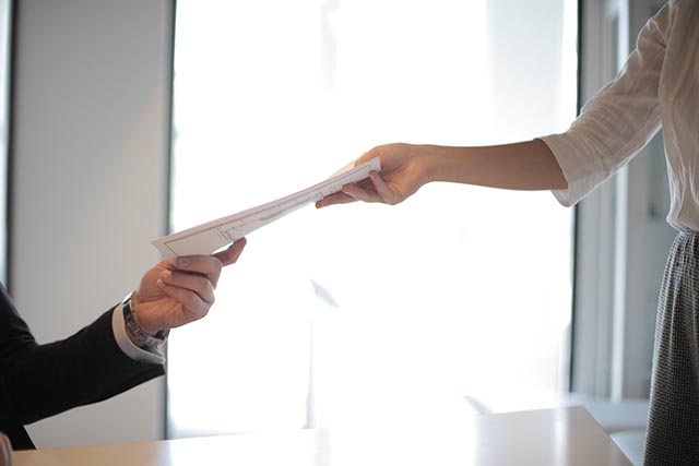 person-handing-another-person-documents