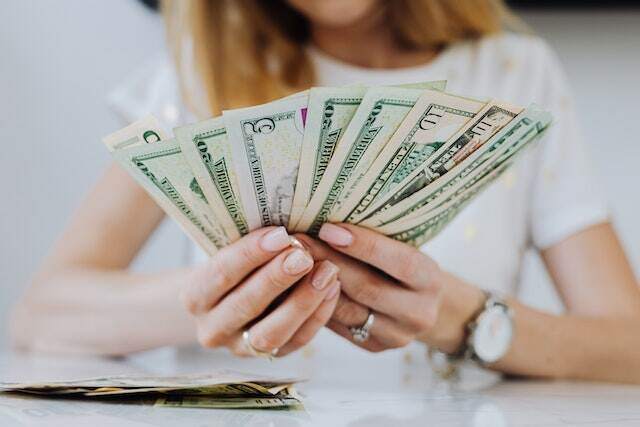 person-holding-rent-dollar-bills-splayed-out-in-their-hands